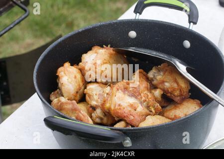 Les cuisses de poulet sont frites dans un chou-fleur en fonte. Cuisiner à l'extérieur. Gros plan. Banque D'Images