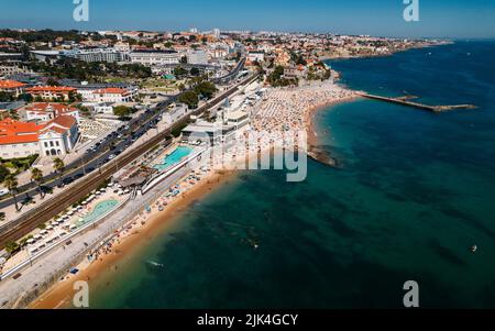 Vue aérienne par drone de la plage surpeuplée de Tamariz à Estoril, Portugal pendant l'été Banque D'Images