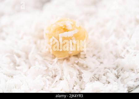 Faire cuire la pâte avec une cuillère à pâte et, après avoir fait rouler les flocons de noix de coco pour cuire les biscuits à la noix de coco. Banque D'Images