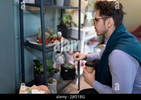 un homme regarde les étagères d'un fleuriste en attendant un bouquet pour lui Banque D'Images
