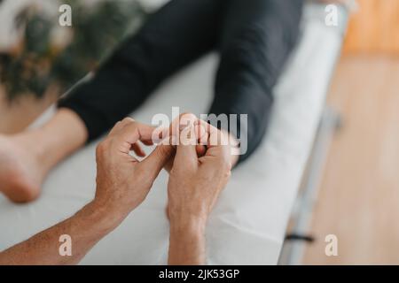 les mains du masseur font de la réflexologie sur les pieds d'une femme Banque D'Images