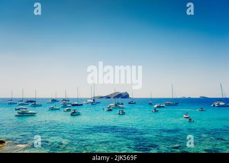 Ibiza, espagne - 28 juillet 2022 : plusieurs bateaux de plaisance ancrés dans une crique sur l'île d'Ibiza pour admirer le coucher du soleil. Banque D'Images