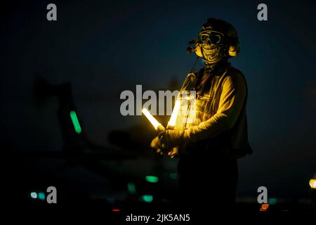 8 juillet 2022 - Océan Atlantique - Aviation Boatswain's Mate (Handling) 3rd classe Ronald Saunders se prépare à diriger un hélicoptère AH-1Z Viper, attaché à l'unité expéditionnaire maritime 22nd, sur le pont de vol du navire d'assaut amphibie de classe Wasp USS Kearsarge (LHD 3) pendant les opérations de vol de nuit 14 juillet 2022. Le Kearsarge Amphiobie Ready Group et a embarqué 22nd Marine Expeditionary Unit, sous le commandement et le contrôle de Task Force 61/2, est en cours de déploiement prévu dans la zone d'opérations de la Marine des États-Unis en Europe, employée par la U.S. Sixth Fleet pour défendre les États-Unis, alliés et partenaires inter Banque D'Images