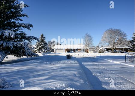 une allée couverte de neige mène au bungalow couvert de neige de l'autre côté de la rue. Banque D'Images