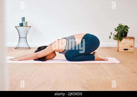 Étirez-vous aussi loin que possible. Une jeune femme pratiquant le yoga à la maison. Banque D'Images
