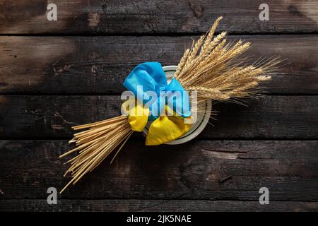 Un tas d'oreilles de blé se trouvent sur une table en bois attachée dans un arc avec le drapeau de l'Ukraine, la guerre mondiale de famine Banque D'Images