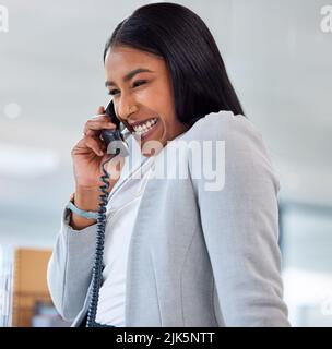 J'aime un client drôle. Une jeune femme d'affaires attrayante assise seule dans son bureau et utilisant un téléphone. Banque D'Images