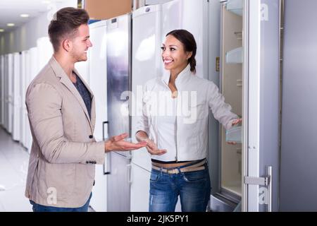 Une jeune famille heureuse qui cherche des réfrigérateurs en magasin Banque D'Images