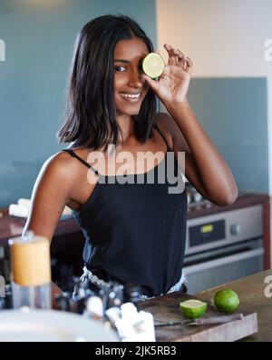 Il suffit d'ajouter une tranche de lime. Une belle jeune femme tenant une tranche de citron sur son œil. Banque D'Images