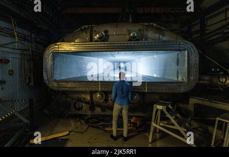Darmstadt, Allemagne. 20th juillet 2022. Un homme se tient devant un composant de l'accélérateur de particules. Le GSI Helmholtz Centre for Heavy Ion Research exploite des installations d'accélérateurs de particules. Actuellement, le centre international des accélérateurs 'Fair' est en cours de construction à Darmstadt. À l'installation, la matière peut être étudiée dans des conditions extrêmes. Credit: Andreas Arnold/dpa/Alay Live News Banque D'Images