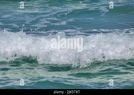 Mousse et éclaboussures sur les vagues côtières. Plage de sable de la mer Méditerranée. Banque D'Images