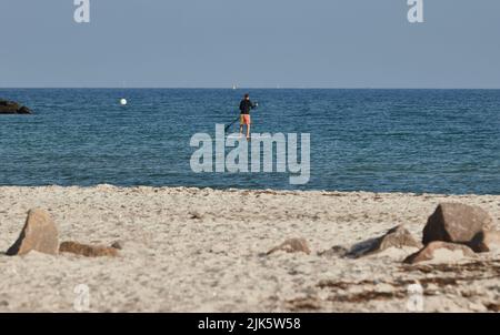 31 juillet 2022, Schleswig-Holstein, Schönberg: Un pagayeur debout sur la plage du Brésil sur la mer Baltique en début de matinée. Photo: Georg Wendt/dpa Banque D'Images