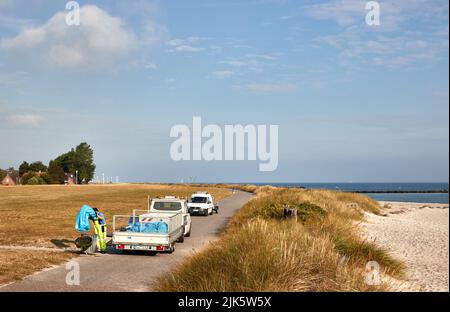 31 juillet 2022, Schleswig-Holstein, Schönberg: Un homme vide une poubelle sur le chemin de la digue sur la plage avec le nom de Brésil. Photo: Georg Wendt/dpa Banque D'Images