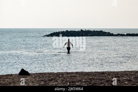 31 juillet 2022, Schleswig-Holstein, Schönberg: Un homme prend une baignade tôt le matin dans la mer Baltique sur la plage au Brésil. Photo: Georg Wendt/dpa Banque D'Images