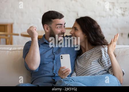 Couple joyeux et enthousiaste tenant un téléphone portable Banque D'Images