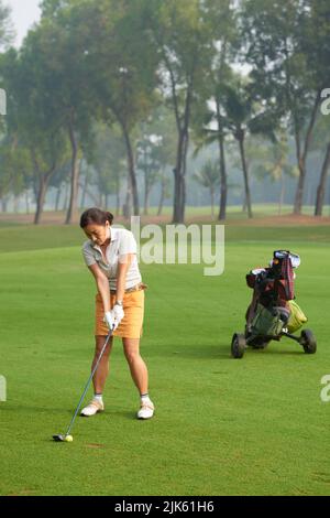 Femme vietnamienne mûre se réjouissant de jouer au golf seul Banque D'Images