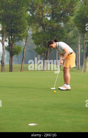 Joueur asiatique de golf féminin concentré sur le jeu Banque D'Images