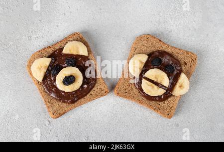 Deux toasts doux pour les enfants en forme d'ours et de singe, avec banane, chocolat et raisins secs, vue du dessus Banque D'Images