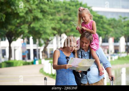Famille de voyageurs à la recherche d'un hôtel sur le plan de la ville Banque D'Images