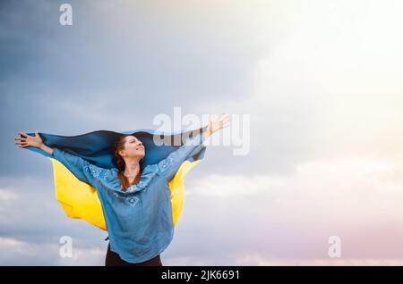 Une femme ukrainienne gratuite heureuse avec drapeau national sur fond de ciel spectaculaire. Portrait de dame en bleu broderie vyshyvanka chemise. Copier l'espace. Ukraine Banque D'Images