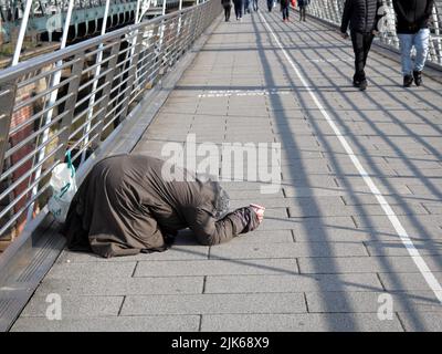 Londres, Royaume-Uni - 07 mars 2021 : une femme pauvre âgée supplie pour de l'argent sur le Golden Jubilee Bridge Banque D'Images