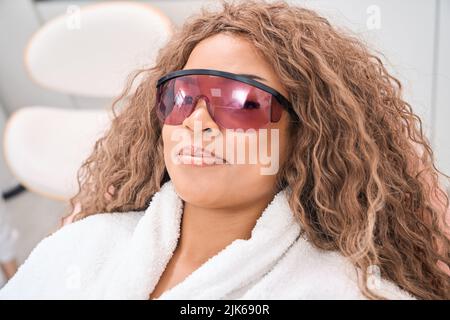 Femme sur le canapé dans des lunettes de protection regardant la caméra Banque D'Images