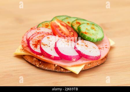 Sandwich croustillant avec concombre frais, fromage, saucisse, radis et tomates sur la planche à découper. Petit déjeuner facile. Sandwichs rapides et sains. Croustillant et garniture savoureuse. En-cas diététiques Banque D'Images