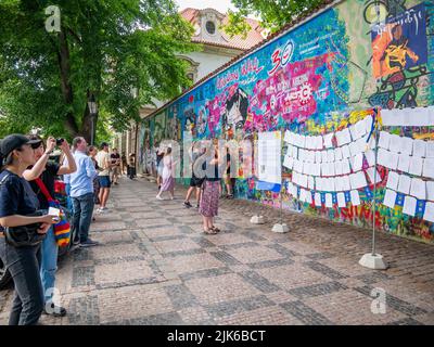 Prague, République Tchèque - juin 2022: Les touristes regardent et prennent des photos du mur Lennon à Prague. Banque D'Images