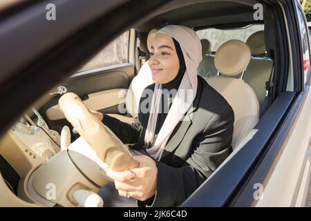 Une femme arabe dans un foulard conduit une voiture Banque D'Images