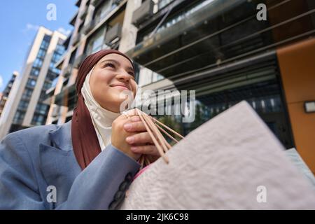 Une femme arabe marche dans la rue avec des sacs après avoir fait du shopping Banque D'Images