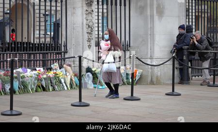 Londres, Royaume-Uni - 10 avril 2021 : femme âgée qui pose des fleurs pour la mort du prince Philippe, duc d'Édimbourg, au palais de Buckingham à Londres Banque D'Images