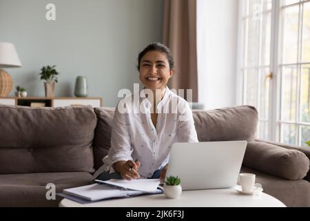 Une jeune femme indienne heureuse travaillant sur un ordinateur portable à la maison Banque D'Images