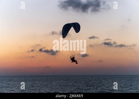 Les hommes volent sur le parachute au soleil Banque D'Images