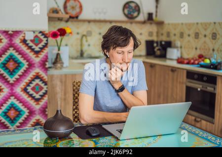 Diffuseur d'huile essentiel sur la table en cours de cuisson pendant que l'homme utilise un ordinateur portable Banque D'Images