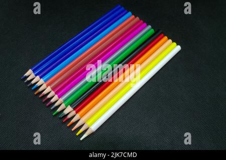 Peinture et dessin : différents crayons de couleur soigneusement disposés en parallèle sur fond noir Banque D'Images