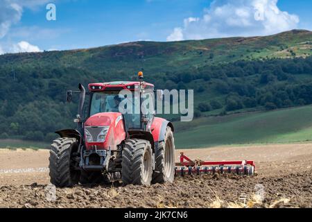 Tracteur McCormick cultivant un lit de semence à la limite des North York Moors, Yorkshire, Royaume-Uni. Banque D'Images