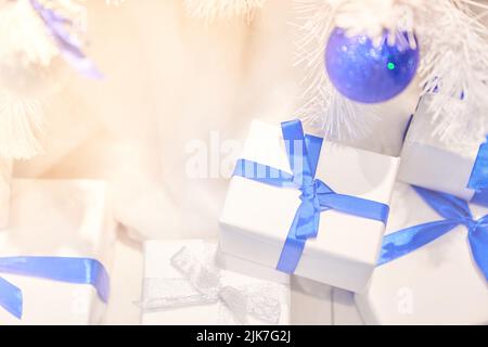 Boîtes blanches de Noël avec rubans bleus sous un arbre blanc de Noël avec ballons bleus. Carte de vœux de Noël et du nouvel an, vacances d'hiver. Photo de haute qualité Banque D'Images