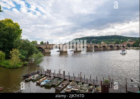 Vue panoramique sur le pont Charles (tchèque: Karlův Most) dans la ville de Prague avec de petits bateaux en bois au premier plan. Banque D'Images