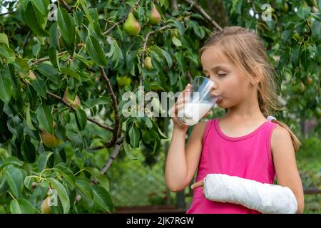 Petite fille mignonne avec un bras cassé dans un lait de boisson moulé Banque D'Images