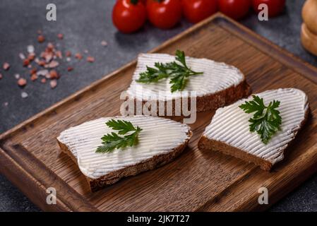 Pain fait maison sur une planche à découper en bois avec du fromage caillé et de la ricotta et des herbes Banque D'Images