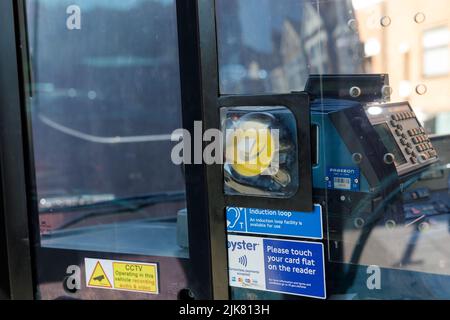 Un terminal de paiement London bus Tap and Go et une signalisation couverte par un écran en plastique sale à l'avant du bus, près du poste de pilotage Banque D'Images