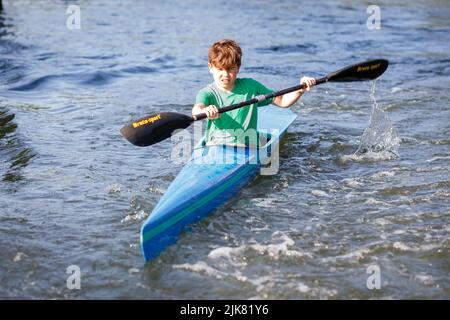 Un jeune kayakiste mâle se pagaie le long de la Tamise par une journée ensoleillée en été. K1 kayak de course. Gros plan Banque D'Images