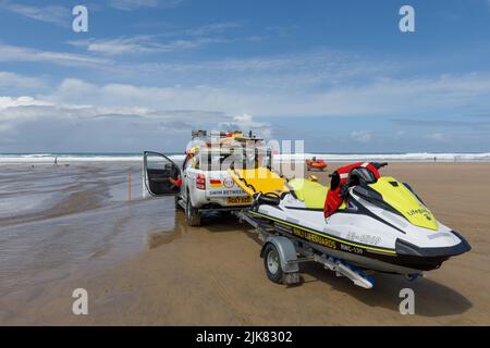 Sauveteurs sur la plage. Un camion de patrouille RNLI se trouve sur la plage avec un coureur de vagues sur une remorque derrière Banque D'Images