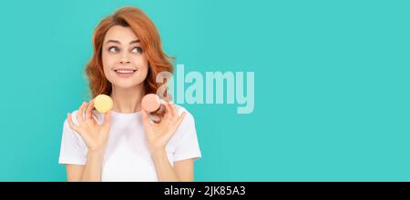 bonne fille tient doux macaron cookie français sur fond bleu. Femme isolé visage portrait, bannière avec maquette d'espace de copie Banque D'Images