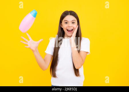 Portrait heureux de l'enfant avec après-shampooing. Soins cosmétiques quotidiens. L'adolescent de 12, 13, 14 ans tient une bouteille de soins pour les cheveux et la peau. Beauté hea Banque D'Images
