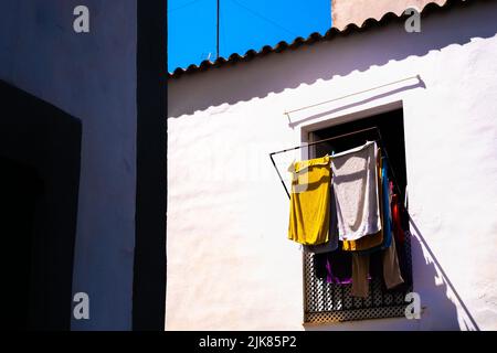 Des vêtements accrochés au soleil pour sécher lors d'une chaude journée d'été en Méditerranée, un mode de vie durable. Banque D'Images