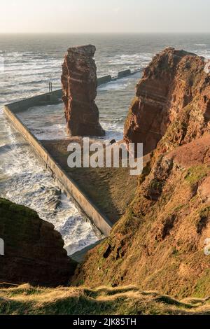 Lange Anna pile de mer et de hautes falaises rouges spectaculaires de l'île d'Heligoland avec mer rugueuse. Une soirée ensoleillée et venteuse à l'heure d'or. Île Helgoland dans le Banque D'Images