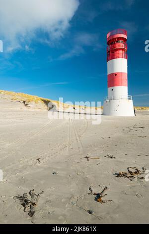 Plan vertical de petit phare rouge et blanc sur la plage de sable de l'île de Dune, Heligoland, lors d'une belle journée d'hiver ensoleillée avec ciel bleu. Banque D'Images