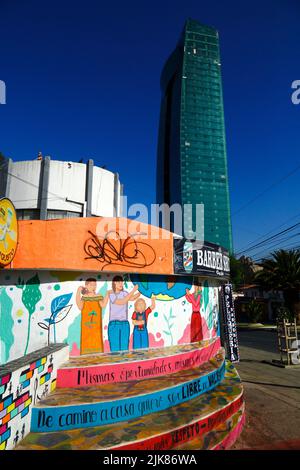 29th juin 2022, AV Ballivian, Calacoto, la Paz, Bolivie. Murale sur le mur d'un salon de coiffure dans le quartier Zona sur de la Paz, peinte par des groupes féministes exigeant l'égalité des chances et des droits pour les femmes, et protestant contre la violence domestique et la violence contre les femmes. En arrière-plan se trouve la tour verte, qui a été achevée en 2022 et avec 46 étages est actuellement le plus haut bâtiment en Bolivie. Il s'agit d'un projet et d'un investissement de la Compañía de Inversiones Comversa S.A. et de l'homme d'affaires bolivien et politisé Samuel Doria Medina. Le bâtiment contient des bureaux et des appartements. Banque D'Images