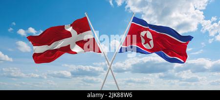 Deux drapeaux croisés la Corée du Nord et le Danemark agitant sous le vent à ciel nuageux. Concept de relation, de dialogue, de voyage entre deux pays. 3d illustration Banque D'Images